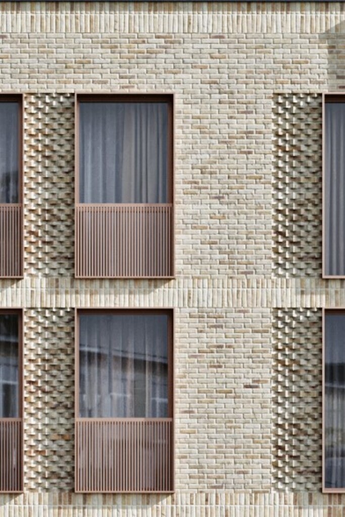 Close-up view of a modern new-build flats facade in London, featuring intricate brickwork and large windows with metal balustrades. This image highlights the detailed architectural design, high-quality materials, and contemporary urban residential development, perfect for maximising investment and ensuring commercial viability in housing projects.