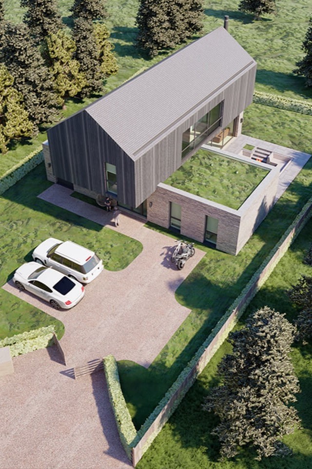 Aerial view of a modern new-build house with eco-friendly design elements in a suburban setting. The property features a contemporary barn-style structure with a green roof, spacious driveway with two parked cars, and a well-manicured garden. Surrounded by lush greenery and mature trees, this innovative home design by London architects captures natural light and provides a seamless connection to the outdoors. Ideal for self-build enthusiasts and property developers seeking sustainable, stylish residential architecture.