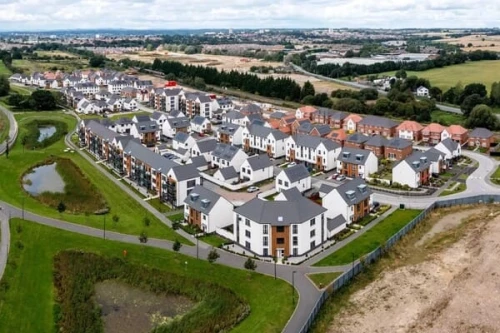 Aerial view of a new-build housing estate with flats and houses arranged around curving streets and green spaces, accompanying Ufuk Bahar’s contribution to RIBA’s article on the draft NPPF and housing delivery.