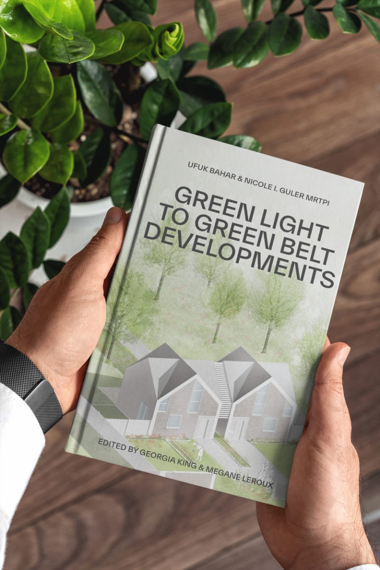 Hands holding a book titled 'Green Light to Green Belt Developments' by Ufuk Bahar and Nicole I. Guler, focusing on development in green belt areas, with a background of lush green indoor plants.