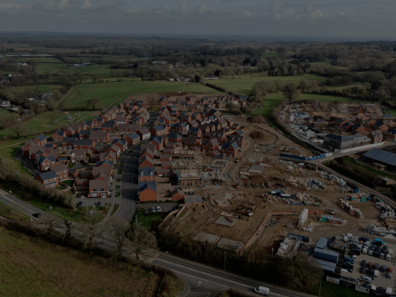 Aerial view of a newly development neighbourhood, alongside another portion of development currently underway in construction, surroudning by green fields and sparsed out dwellings